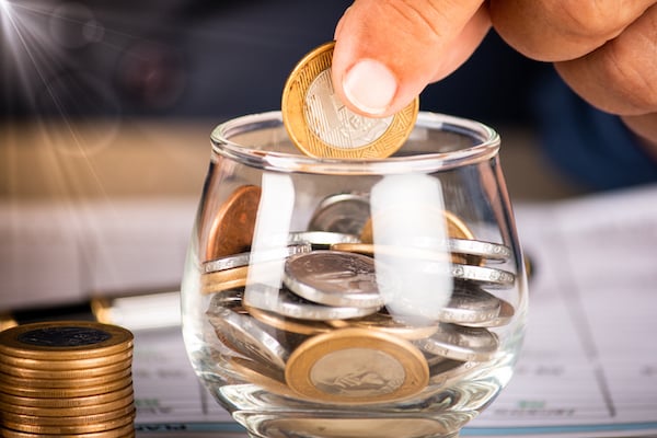 businessman-holding-coins-putting-into-glass-pot-saving-concept-financial-accounting