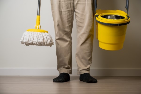 man-standing-holding-yellow-mop-bucket