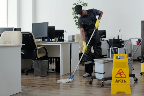 contemporary-young-black-man-workwear-cleaning-floor-openspace-office